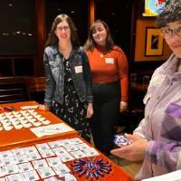 Three alums standing at the welcome table together.